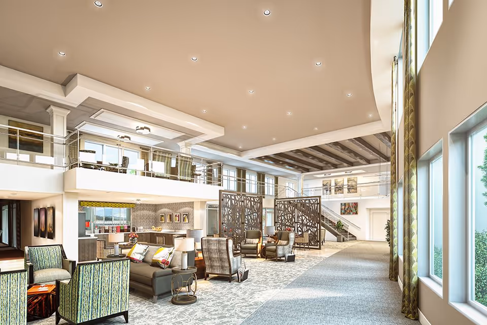 Spacious and modern senior living facility common area with high ceilings, large windows, and natural light. The room features comfortable seating including armchairs and sofas arranged in conversation groups, decorative room dividers, and a mezzanine level with additional seating. The decor includes patterned carpets, curtains, and contemporary artwork on the walls.
