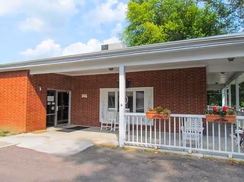 Brick building entrance of Elms Health Care Center with a covered porch and planters.