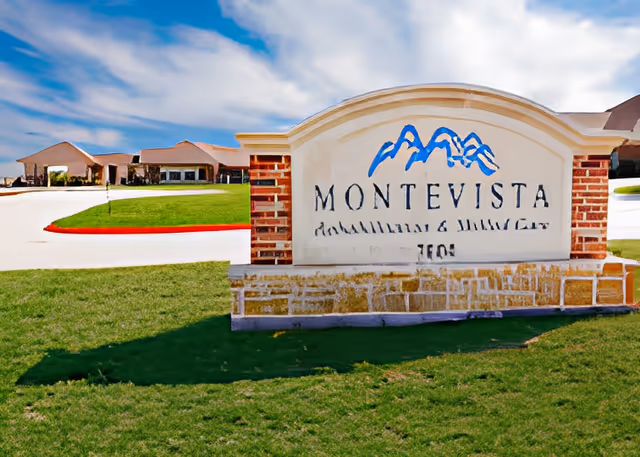 Outdoor view of the entrance sign for Montevista Rehabilitation & Skilled Care facility, with a clear blue sky and buildings in the background.