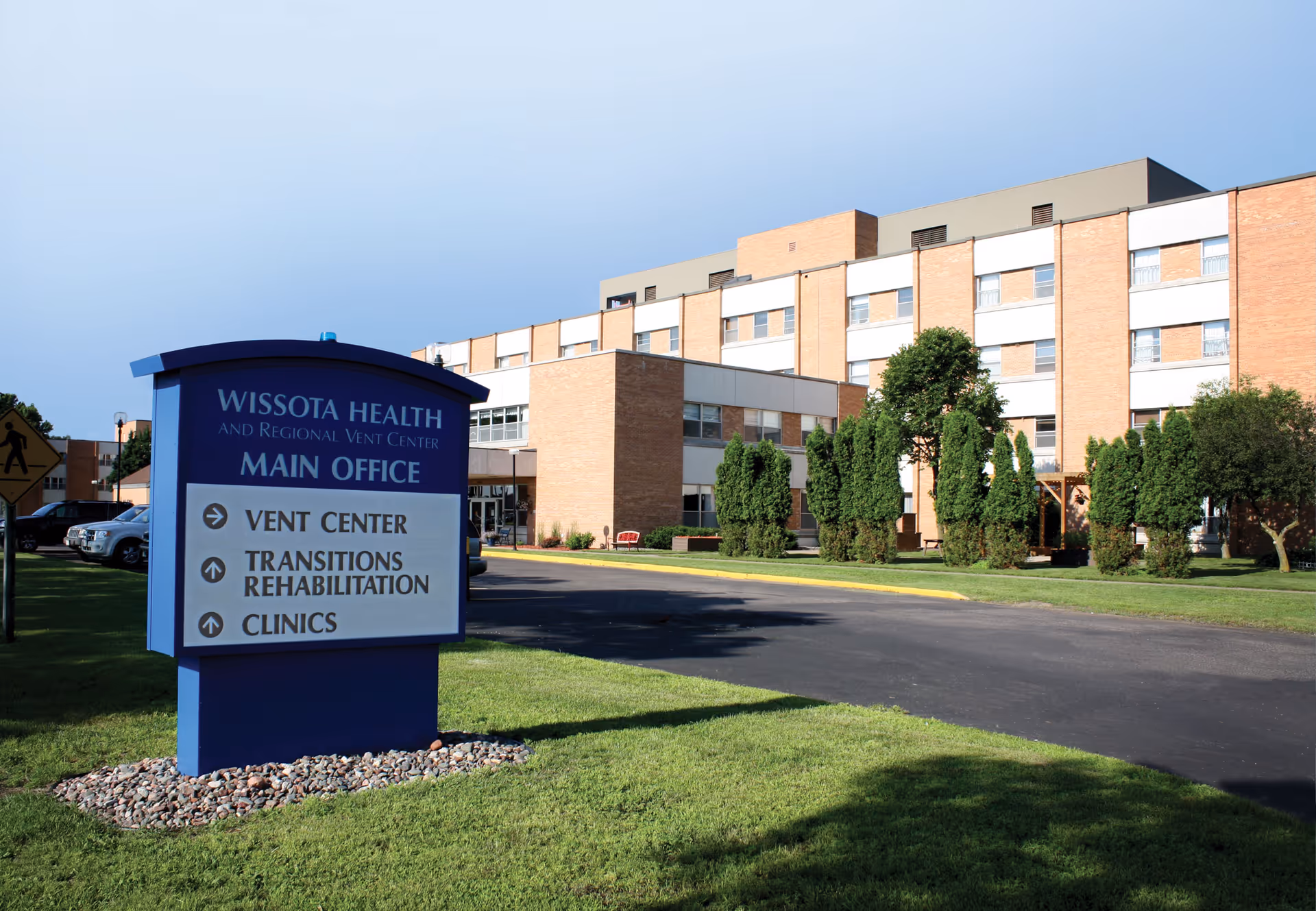 Exterior front view of Wissota Health and Regional Vent Center building with a blue main office sign on the lawn.