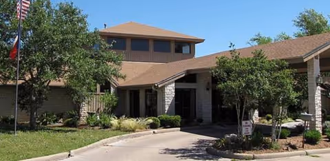Exterior view of Schulenburg Regency Nursing Center entrance with landscaping and flag.