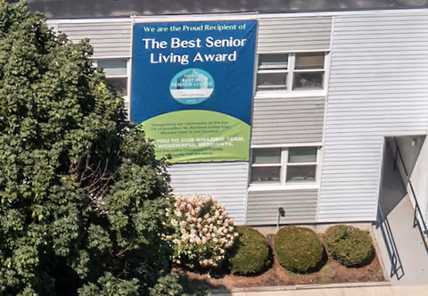 Exterior of The Magnolia senior living building with a blue award banner.