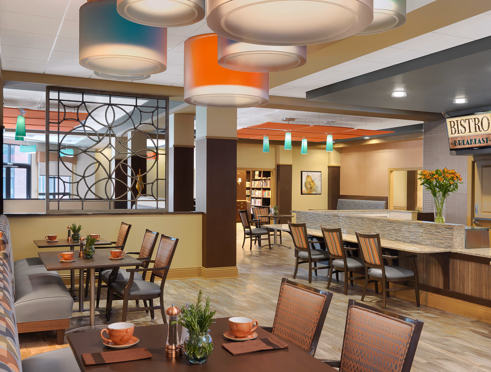 Bright, modern dining/bistro area with tables, chairs, counter seating, pendant lights and a decorative room divider.