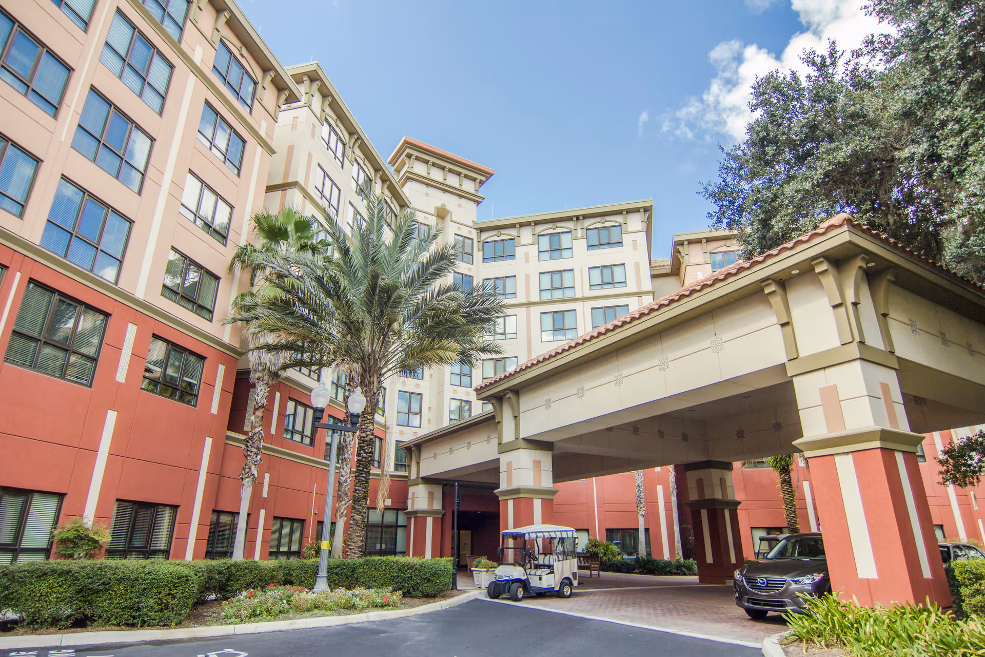 Exterior view of Freedom Pointe senior living showing a porte-cochere entrance and palm trees.