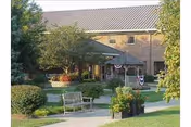 Front entrance and landscaped courtyard of Thomson-Hood Veterans Center with benches, walkways, trees, and the building facade.