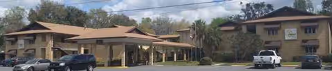 Camelot Chateau Assisted Living exterior with covered entrance and parked cars.