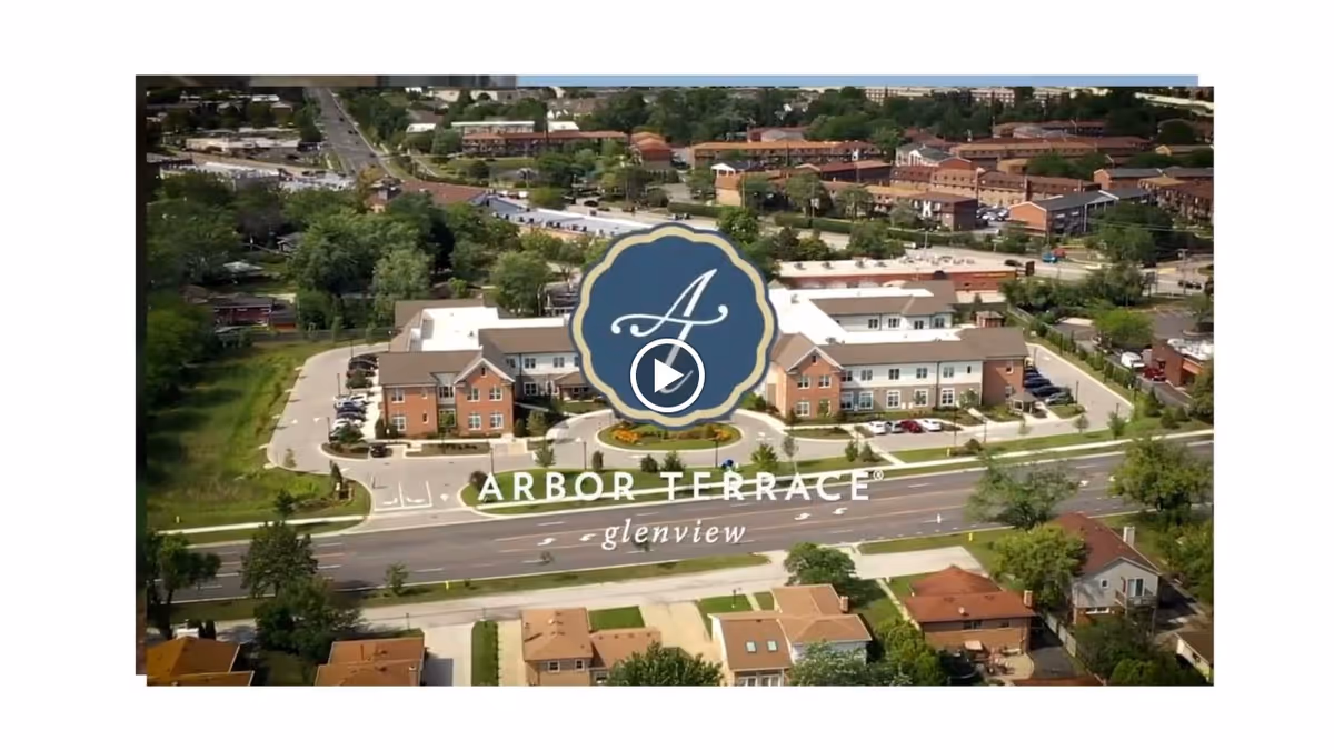 Aerial view of Arbor Terrace Glenview senior living facility showing a large building with surrounding parking lots, roads, and nearby residential houses and greenery.