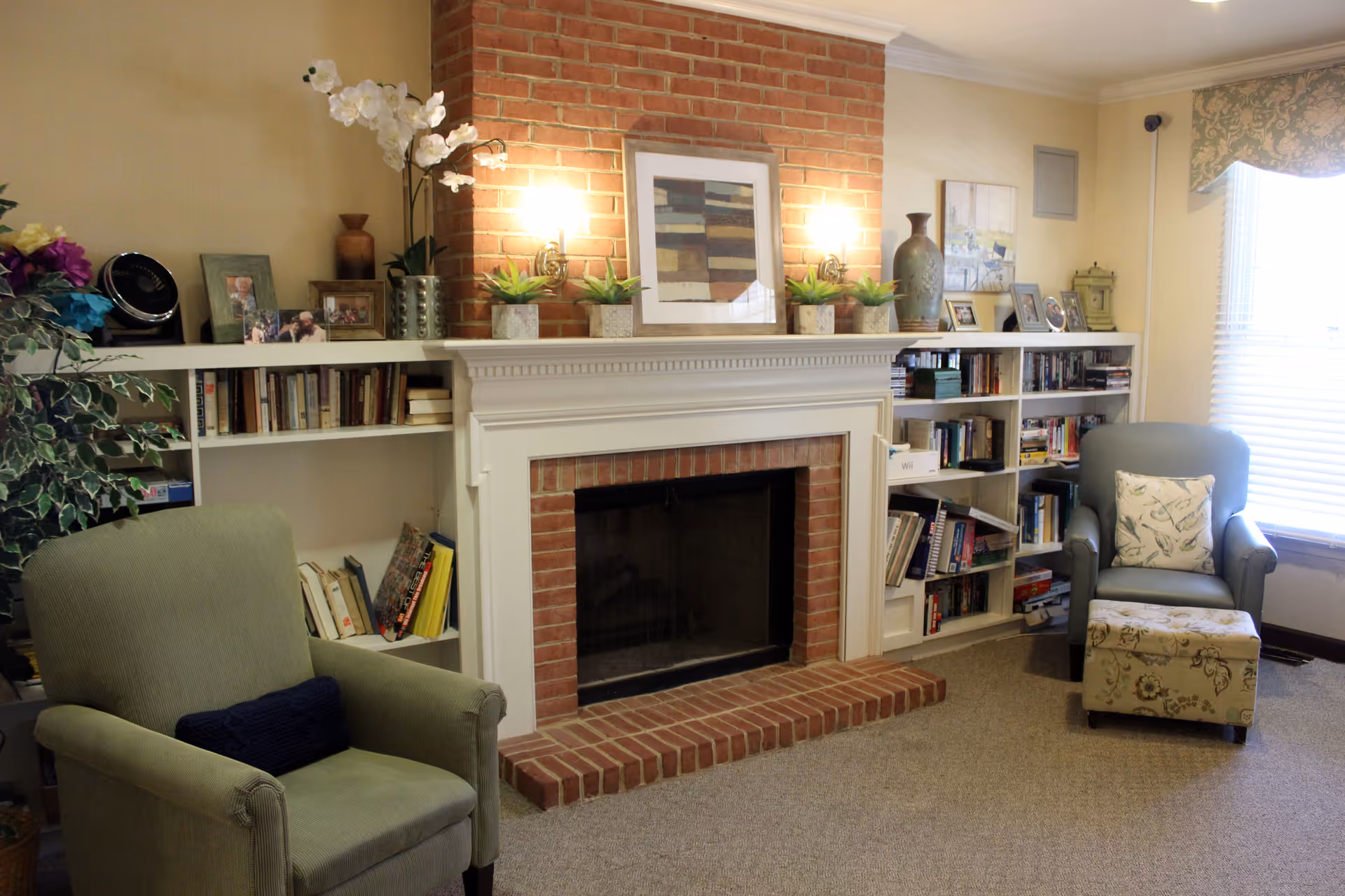 Cozy living room with a brick fireplace flanked by built-in bookshelves, two armchairs and decorative accents.