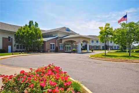 Front exterior of Huntington Hills Center for Health and Rehabilitation with entrance and flag.