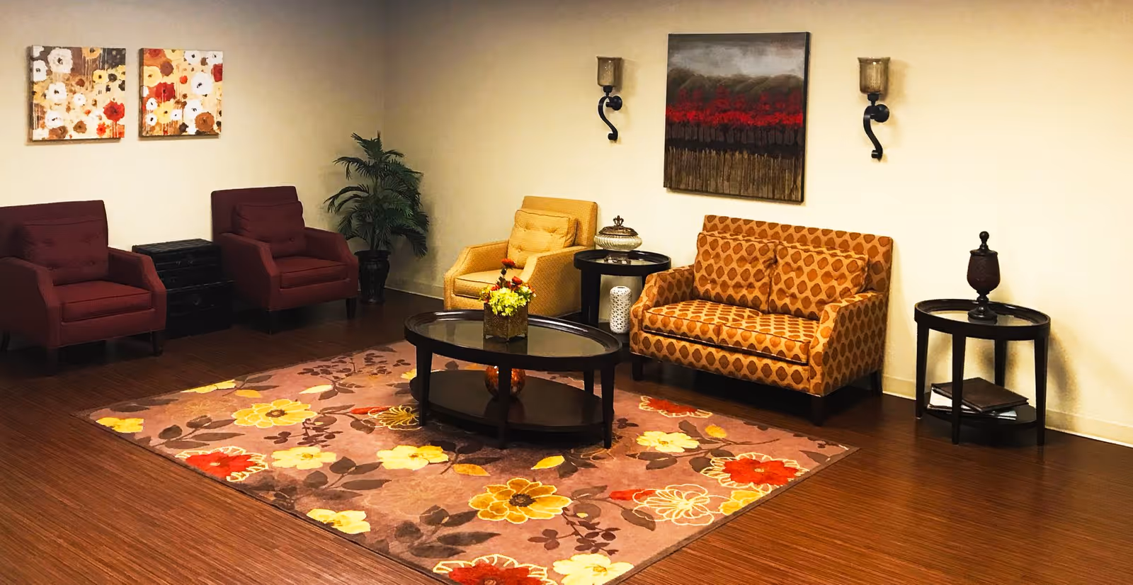 Cozy seating area with armchairs, a patterned sofa, round coffee tables and a floral rug against a neutral wall.
