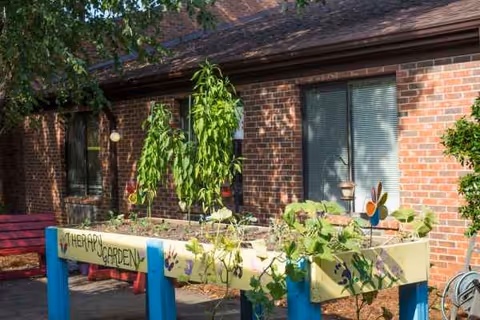 Outdoor therapy garden in front of a brick building with raised planters and a bench.