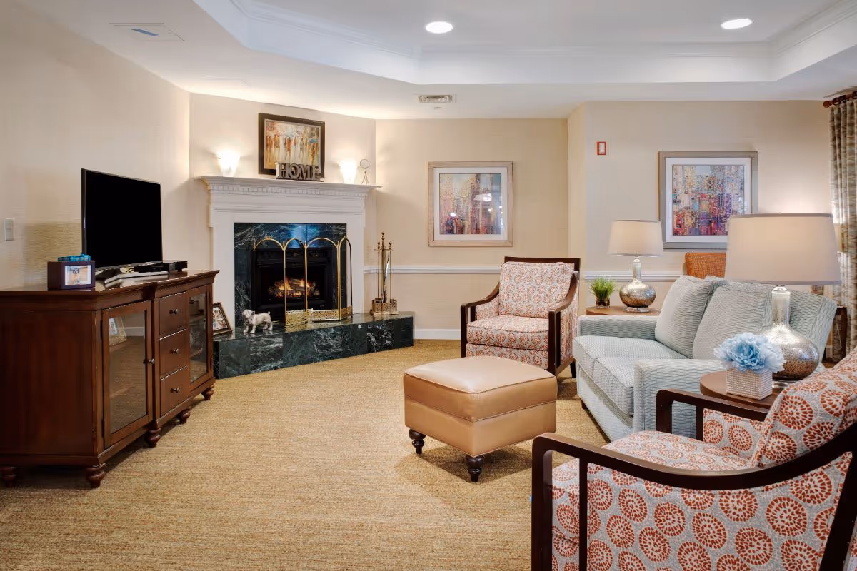 Comfortable communal living room with sofa and armchairs arranged around a fireplace and television.