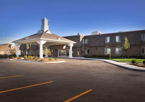 Exterior view of Rivergate Health Care Center with a covered entrance and parking lot.