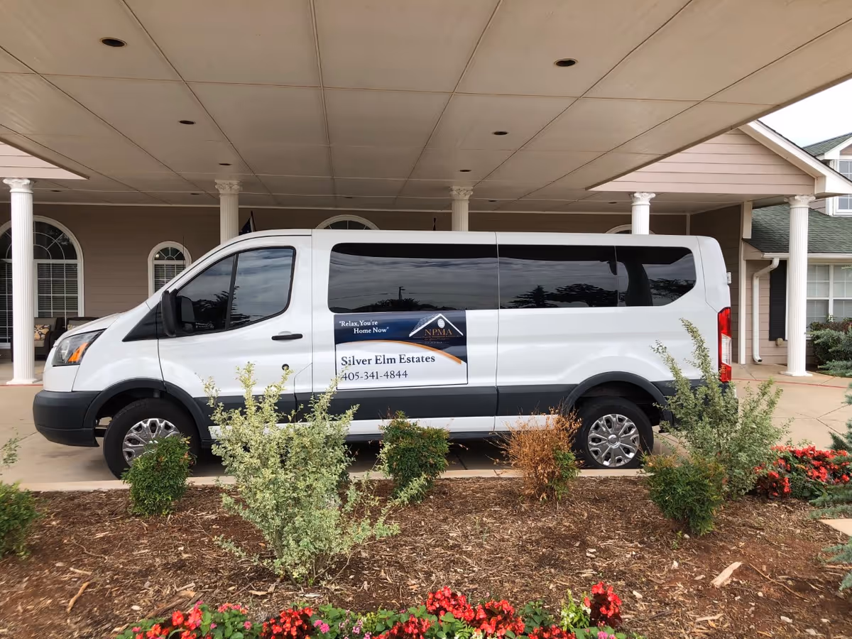 White van with Silver Elm Estates logo parked at the entrance of Edmond senior living facility.