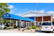 Exterior view of Allure of Quad Cities entrance with blue canopy and parked car.