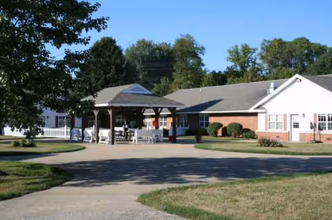 Single-story brick nursing facility with a covered entrance and surrounding trees.
