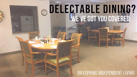 Dining area with wooden tables and chairs set with cups and plates. In the background, there is a kitchen window and a refrigerator. Text overlay reads 'DELECTABLE DINING? WE'VE GOT YOU COVERED.' and 'DAYSPRING INDEPENDENT LIVING'.
