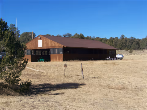 Brown barn-style building in a dry field with a propane tank nearby.