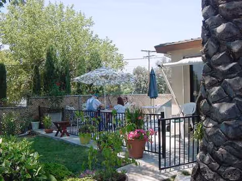 Outdoor patio at Mom's House with residents seated at a table under umbrellas.