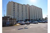 Exterior view of Jefferson Center: a tall beige senior living building with a parking lot.