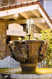 A decorative fountain is in the foreground with a Welcome sign and the facility exterior behind.