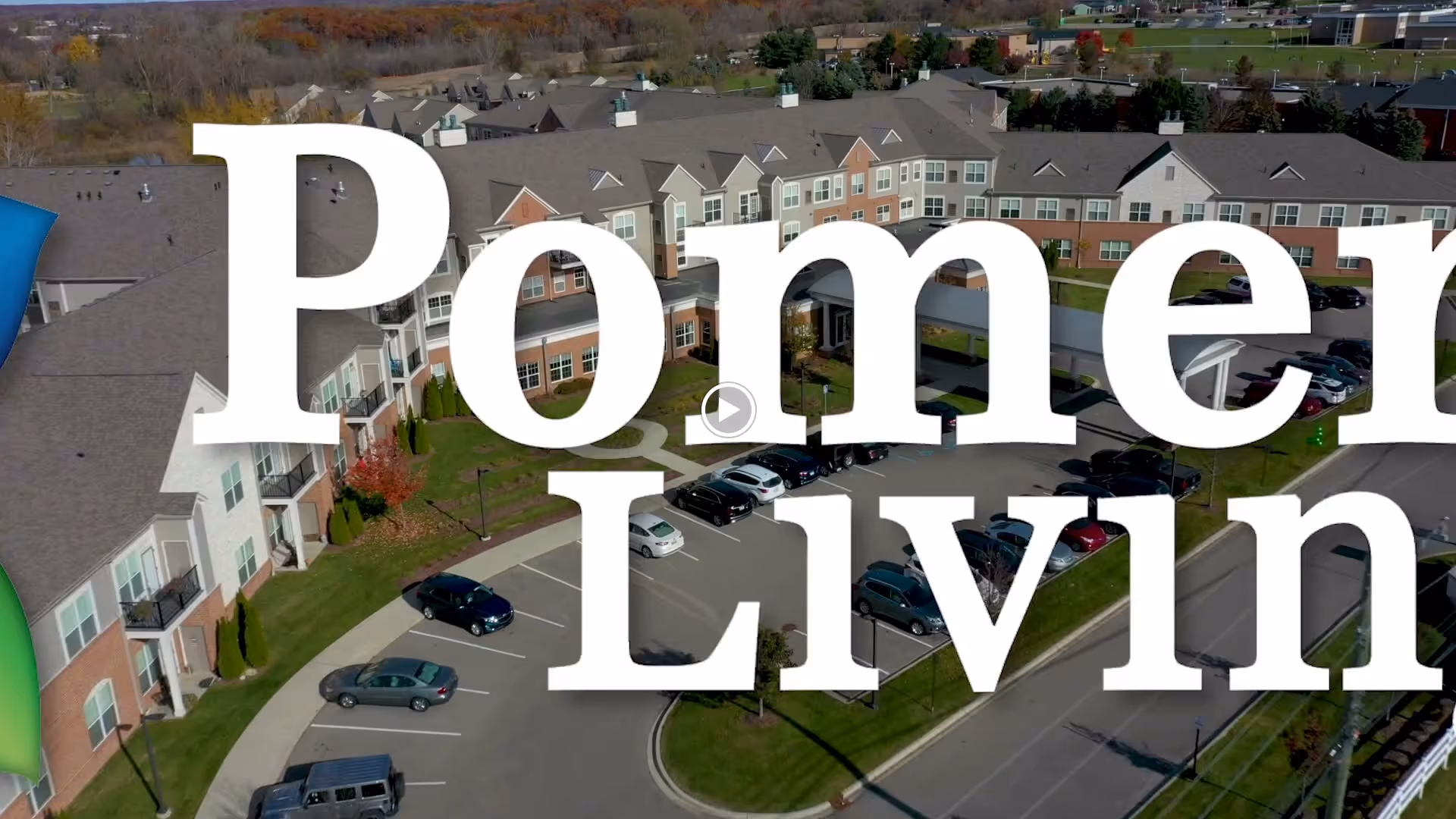Aerial view of Pomeroy Living Orion Assisted Living facility showing a large, multi-wing building with a parking lot and surrounding greenery under a clear sky.