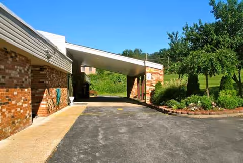 Brick senior living facility entrance with a covered driveway and landscaped front yard.