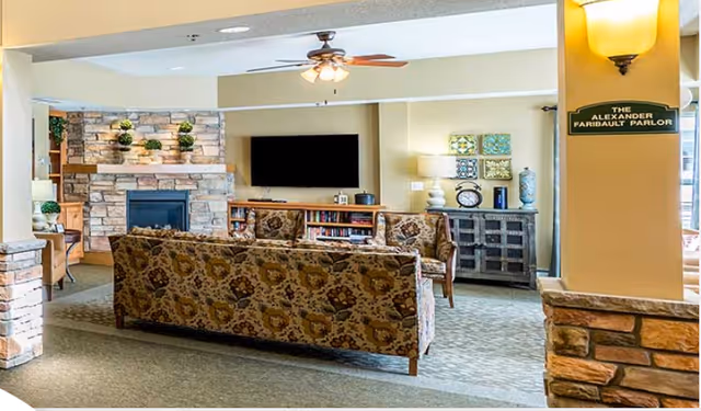 Comfortable lounge with patterned sofas facing a wall-mounted TV, stone fireplace, and decorative shelving.