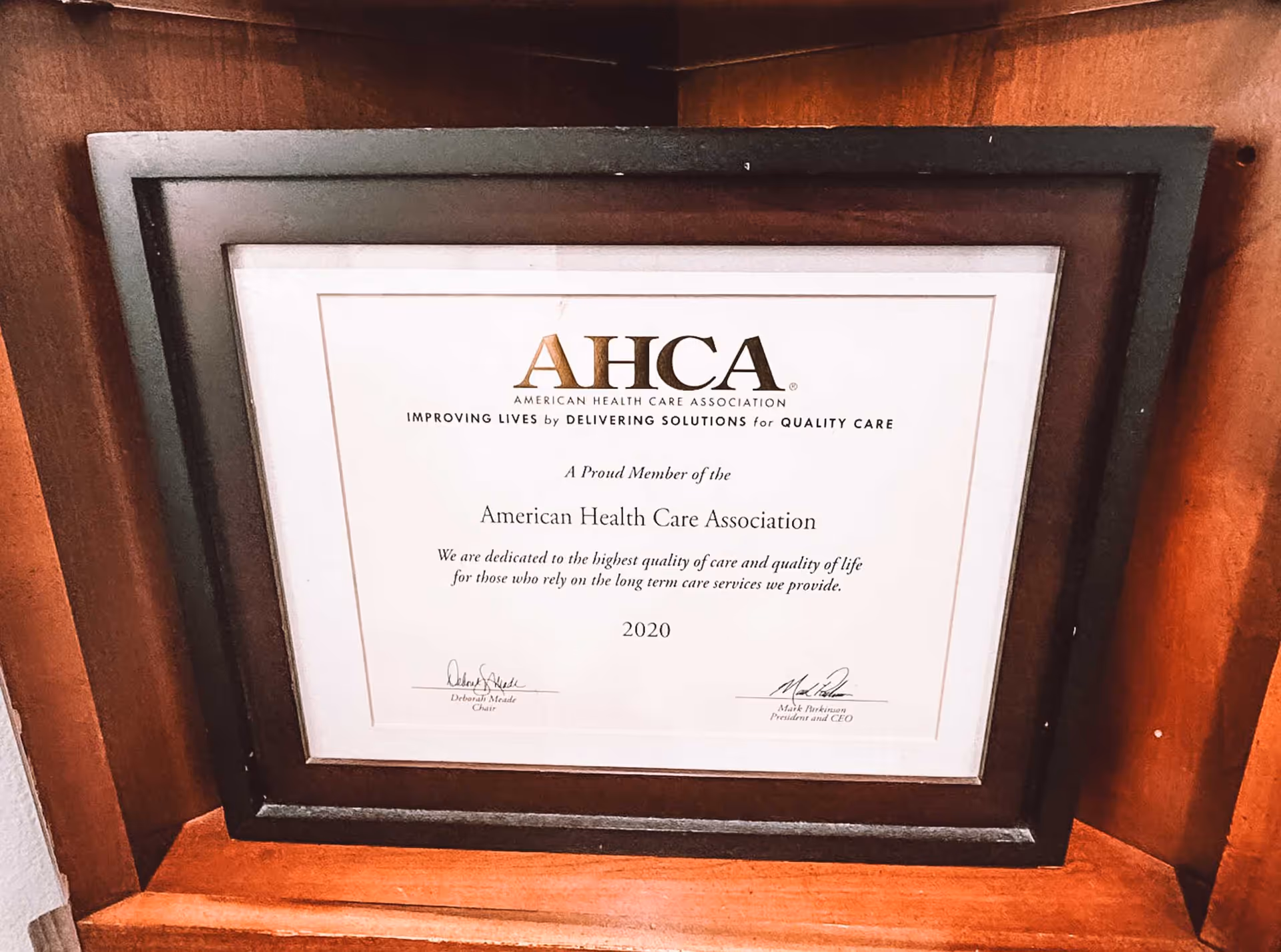 Framed certificate from the American Health Care Association (AHCA) awarded in 2020, displayed on a wooden surface.