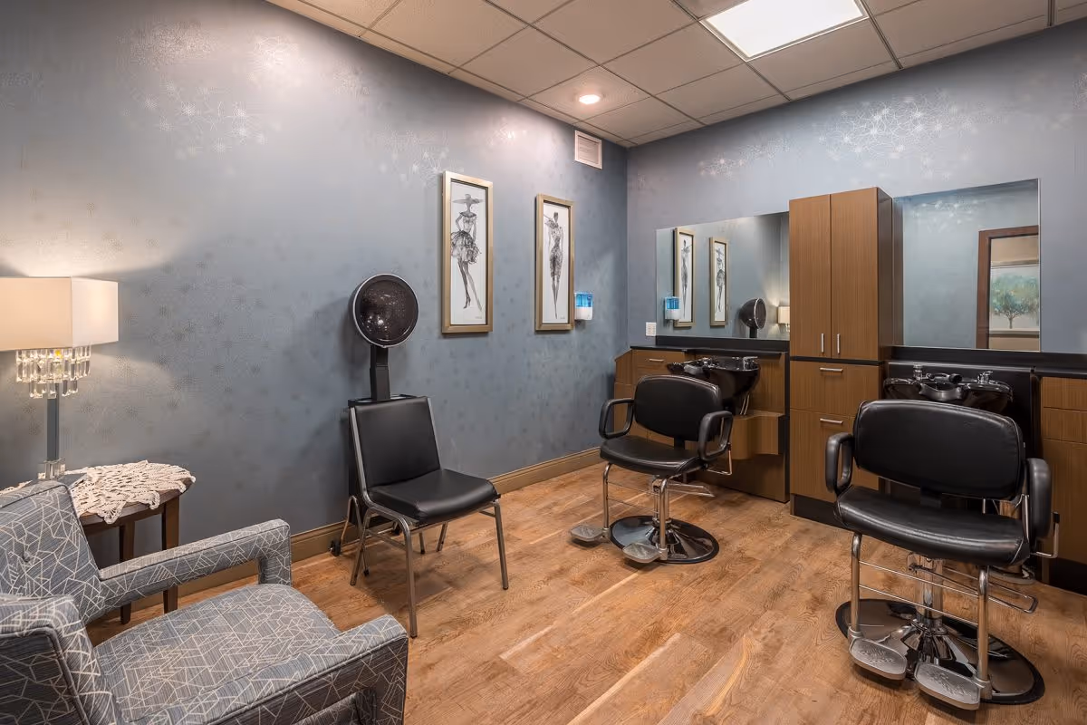 Interior salon room with styling chairs, hair-dryer hood, shampoo sinks, cabinetry and seating.