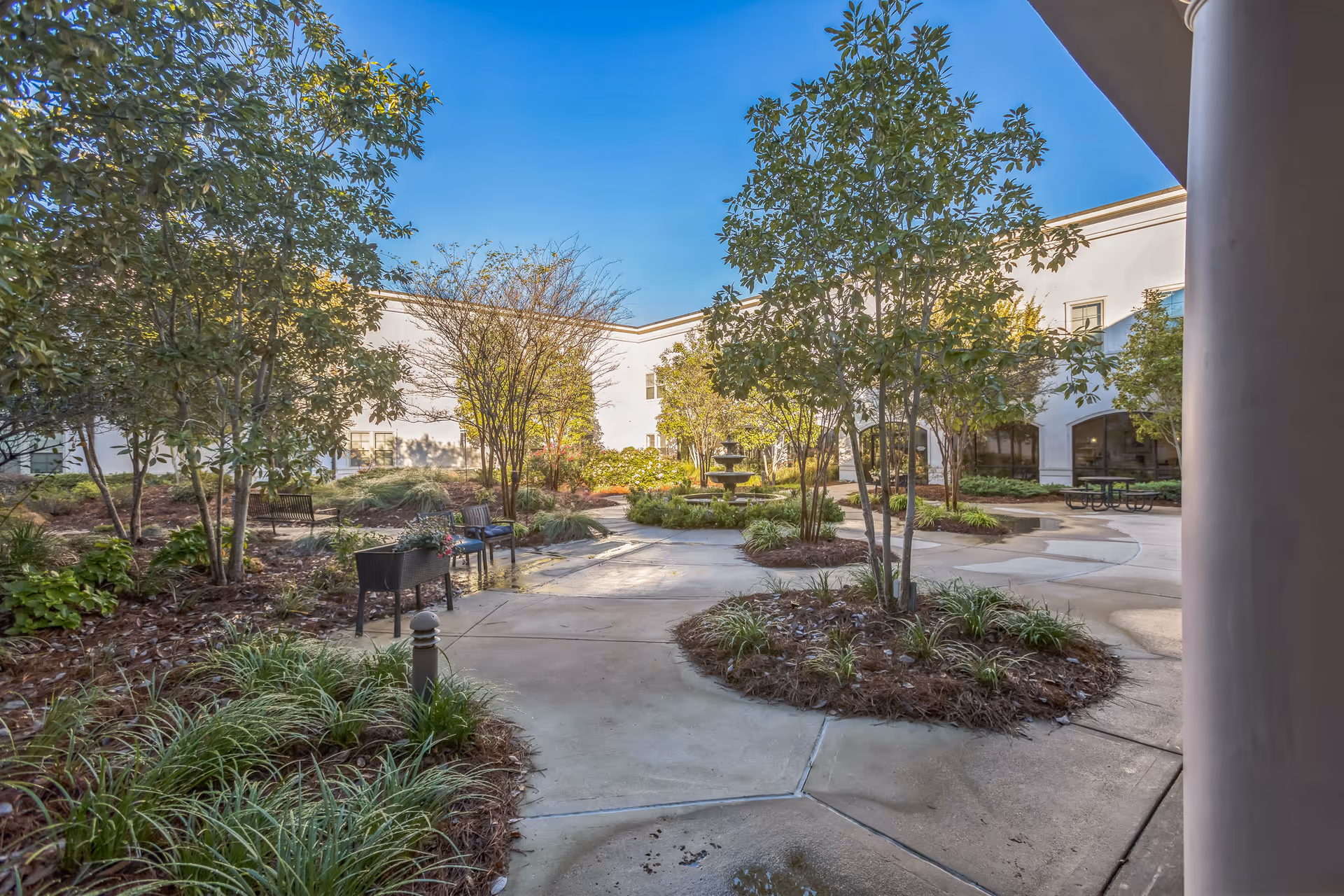 Enclosed courtyard with paved walkways, planted beds, seating and a central fountain framed by the surrounding building.