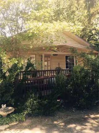 Small lodge-style building with a front porch surrounded by leafy trees.