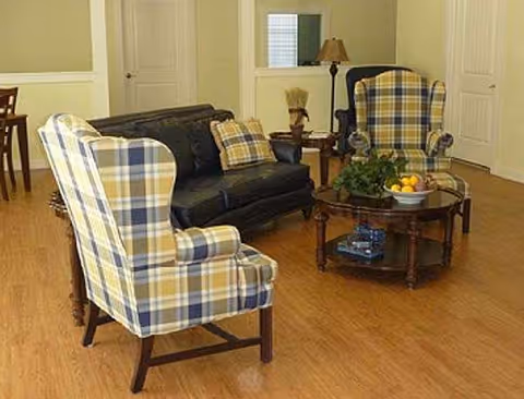 Cozy living room with plaid chairs, a black sofa, coffee table, and fruit centerpiece.
