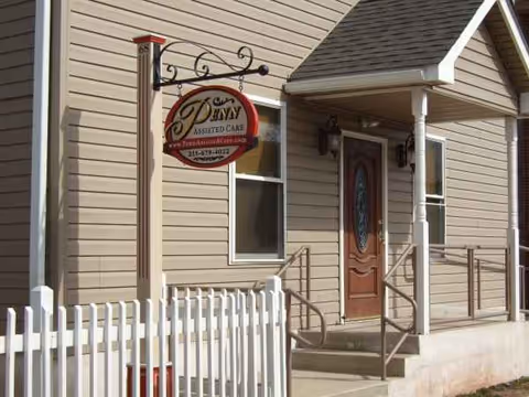 Exterior view of a beige assisted living facility with a porch and entrance sign.
