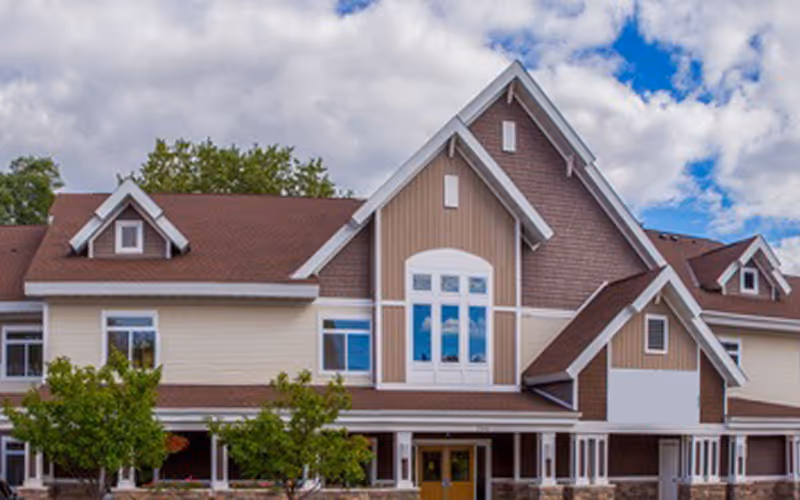 Front exterior view of a multi-story senior living facility with gabled roof.