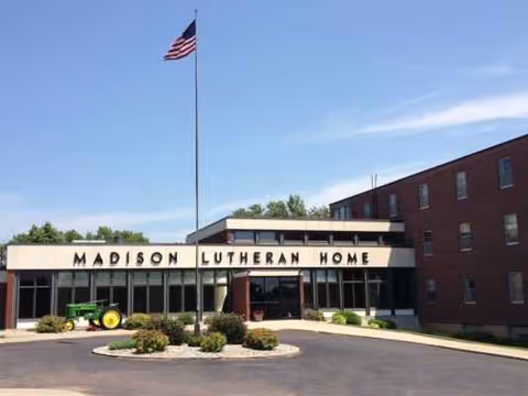 Front view of Madison Lutheran Home facility with flagpole and landscaped entrance