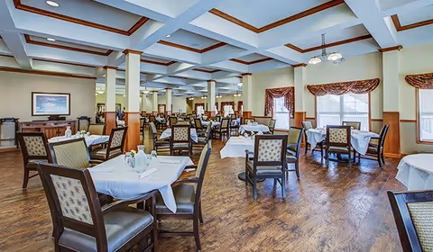 Spacious dining room with multiple set tables and chairs under a coffered ceiling.