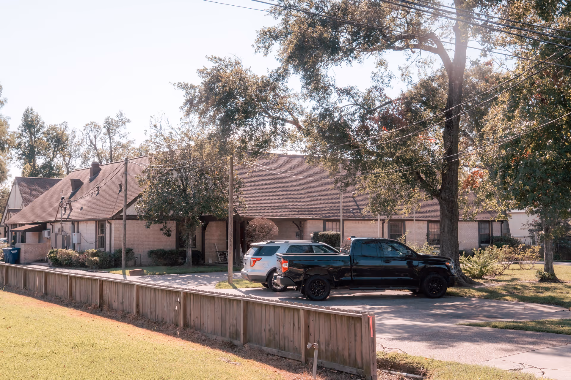 A view of Mountbatten House's exterior, featuring a single-story building with a sloped roof, surrounded by trees and parked vehicles.