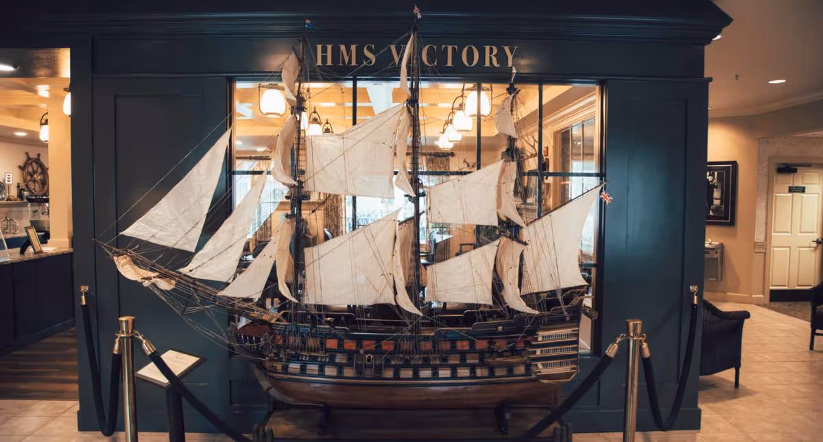 A large detailed model of the ship "HMS Victory" displayed behind ropes in an interior lobby area.