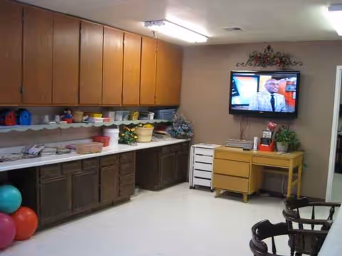 Interior activity room with wall of cabinets, craft supplies, a TV, and balloons.