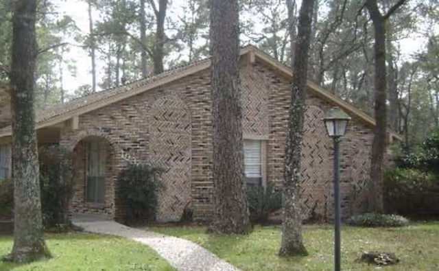 Brick, single-story building front with a walkway, trees, and a lamppost.