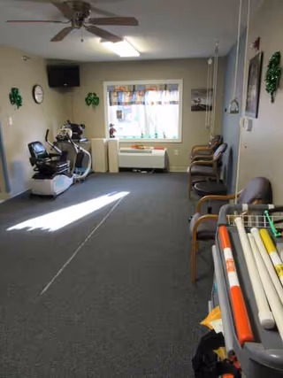 An indoor activity room with chairs along the wall and exercise equipment.