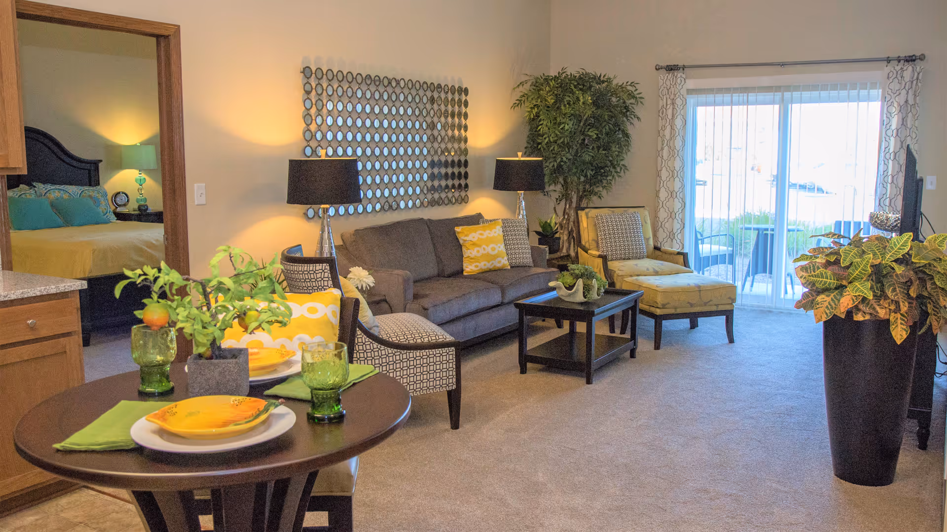Bright furnished living room and dining area with a sofa, chairs, small dining table, and sliding glass door to a patio.