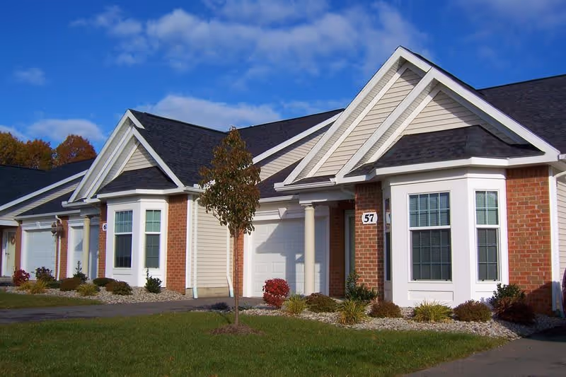 Exterior view of a residential building at Legacy at Clover Blossom, featuring a brick facade, gabled roof, and landscaped front yard.
