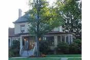 Front view of a two-story senior living facility with a porch and landscaping.