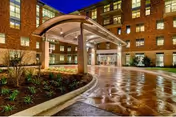 Wet brick exterior of Westminster senior living entrance with curved canopy and landscaping