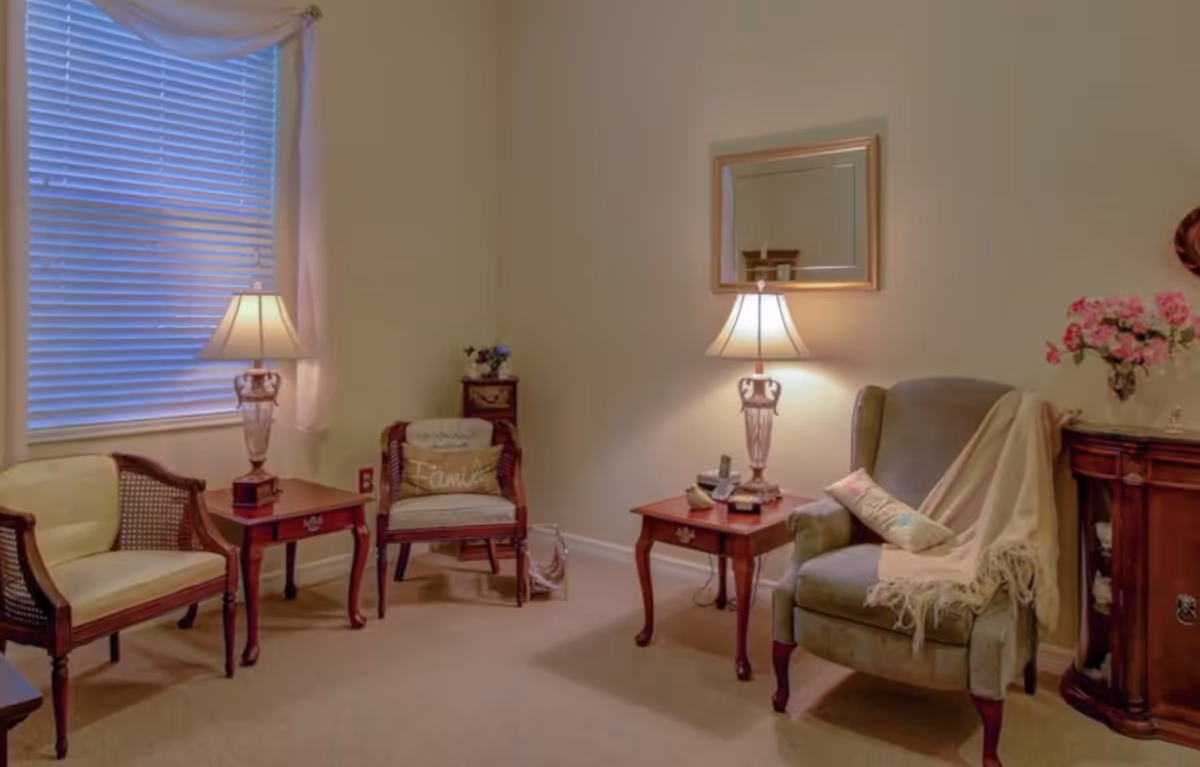 Comfortable sitting room with upholstered armchairs, wooden side tables, table lamps, and floral decor.