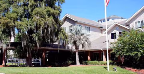 Exterior view of River's Edge by Barclay House showing the building front, trees, and lawn.