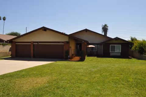 Single-story front exterior with a two-car garage and a green lawn.