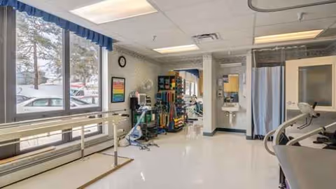 Interior of a senior living facility with medical equipment, privacy curtains, and a window.